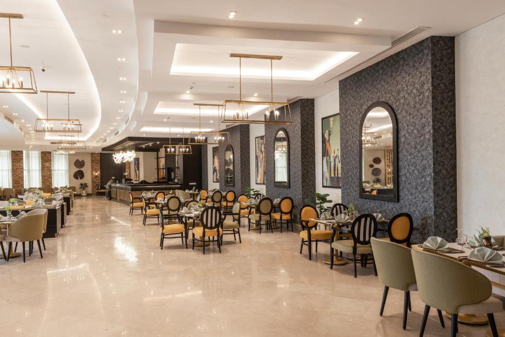 Gewan Resort New Alamein في العلمين: مطعم به طاولات وكراسي وغرفة طعام