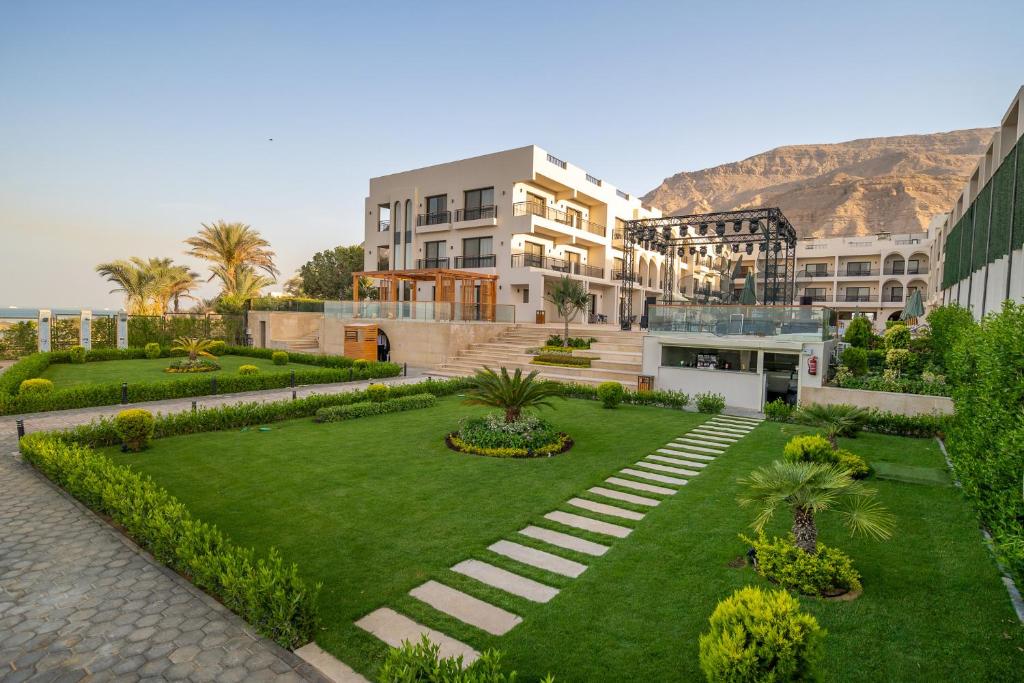 Al Masa Hotel El Sokhna في العين السخنة: مبنى ذو حديقة ومبنى آخر تظهر الجبال في خلفيته